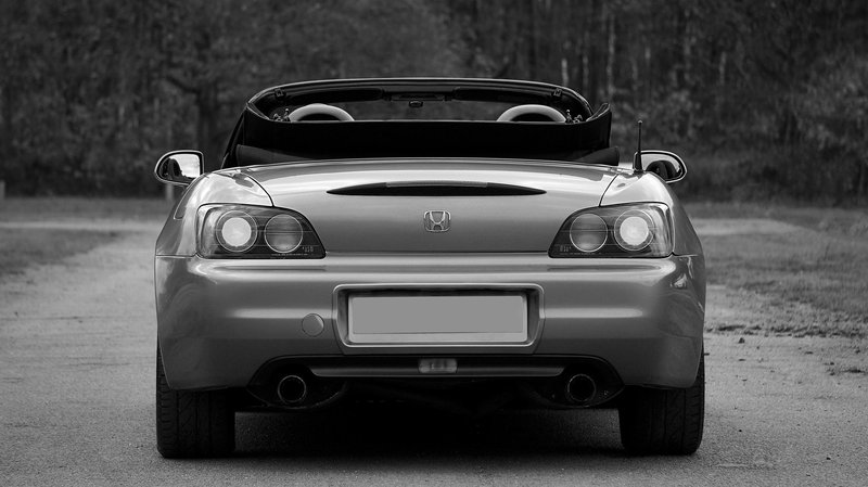 Rear view of a luxury convertible car parked with a classic style in a monochrome setting.
