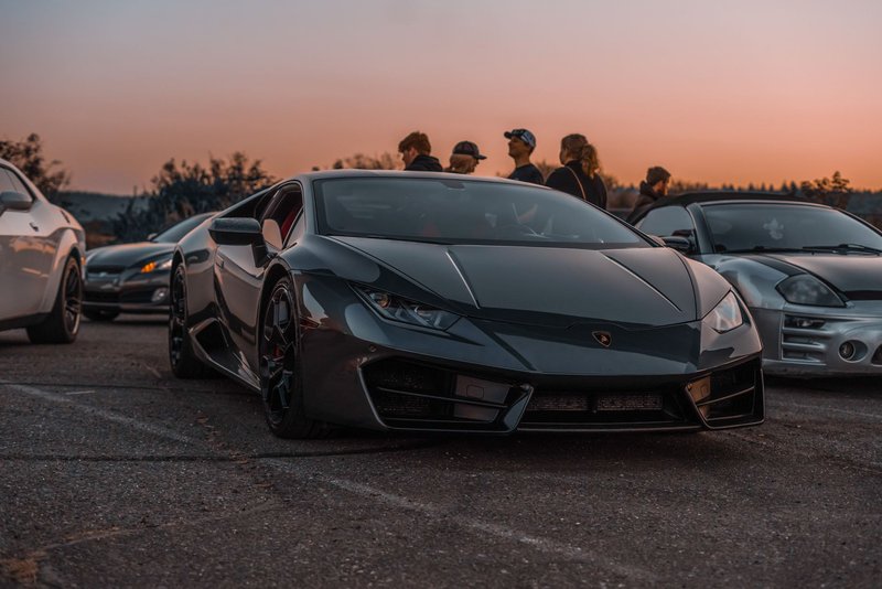 Lamborghini sports car with others at a sunset meet, exuding luxury and style.