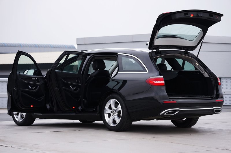A luxury black Mercedes wagon with all doors open, parked outdoors.