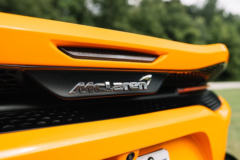 Detailed view of a luxurious orange sports car featuring the iconic McLaren logo.