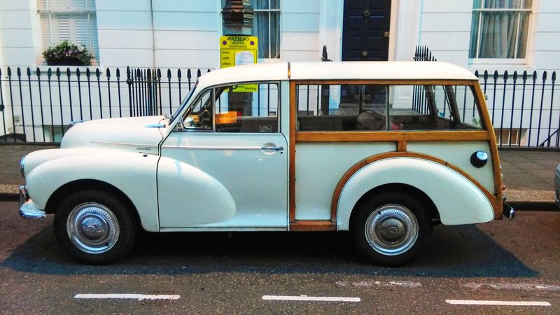 Vintage white Morris Traveller car parked on a London street with wooden framing.