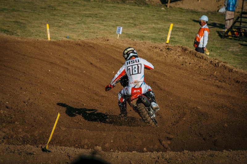 Dynamic action shot of motocross racer turning a dirt track corner during competition.