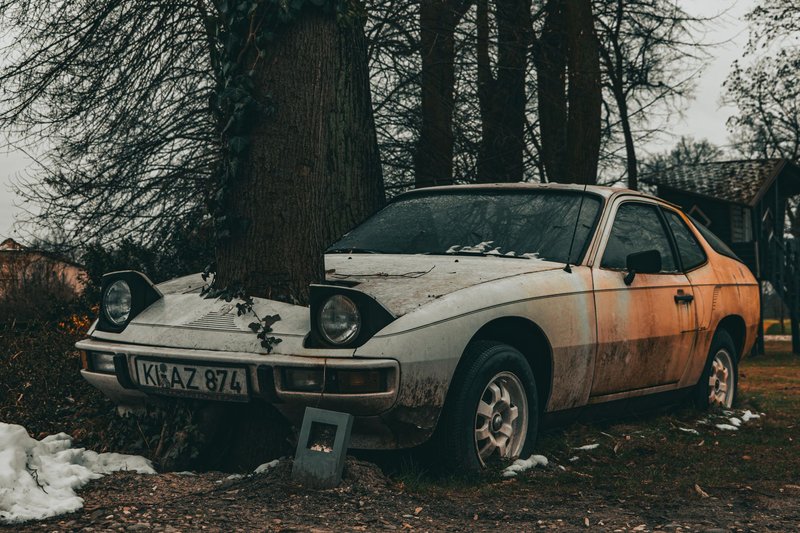 An old rusty car abandoned in a forest, overgrown with ivy. Perfect for themes of neglect or decay.