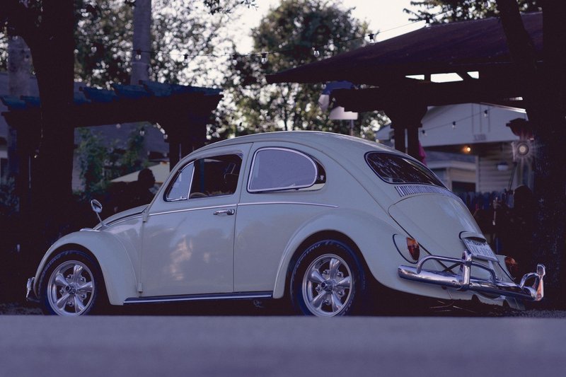 A vintage Volkswagen Beetle sits parked outdoors in Houston during the evening.