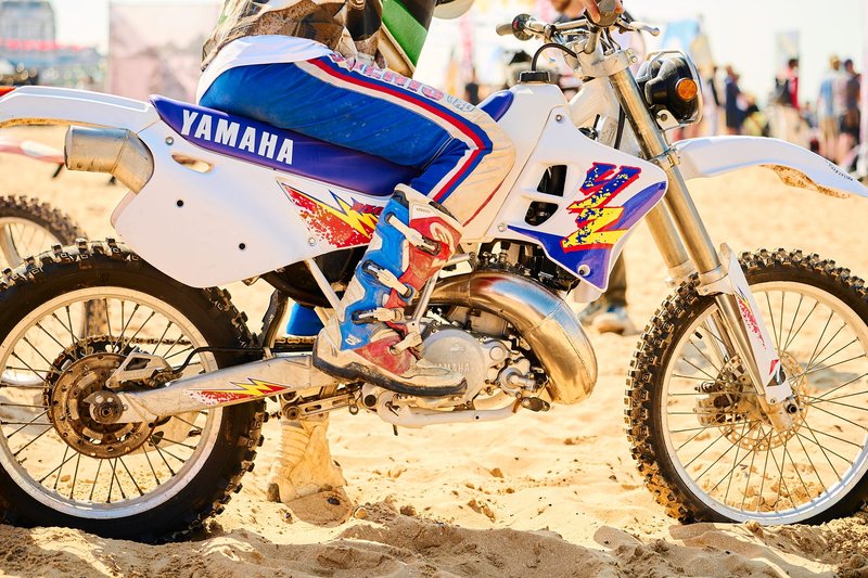 A motocross racer rides a Yamaha dirt bike on Margate beach during a sunny day.