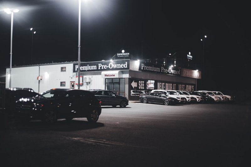 Illuminated car dealership lot showcasing premium pre-owned vehicles at night.