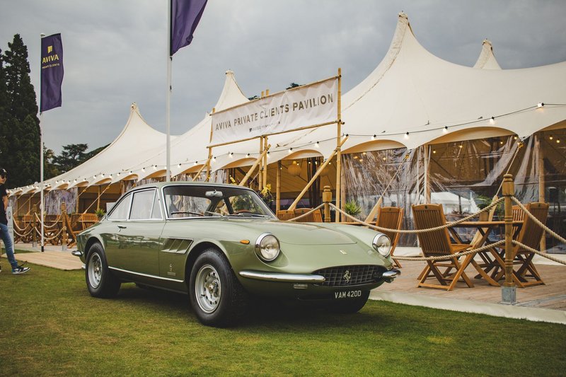 A classic green car parked by an elegant outdoor pavilion setup.