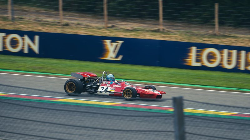 Vintage red race car speeding at the Spa-Francorchamps track in Belgium.