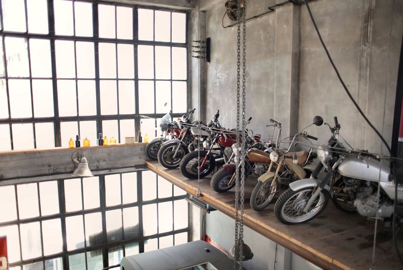Several retro motorcycles placed in row on special platform in garage near wall and big windows
