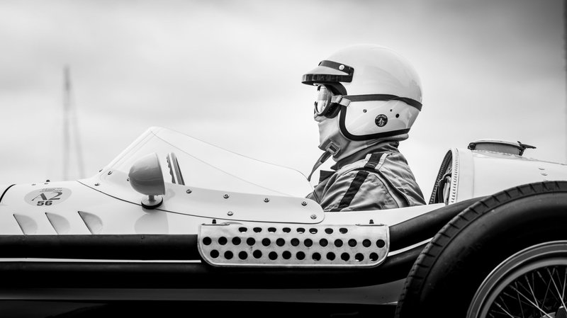 Side profile of a vintage race car driver in helmet ready to race.