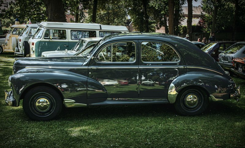 Vintage car showcased at outdoor auto exhibition among classic vehicles.