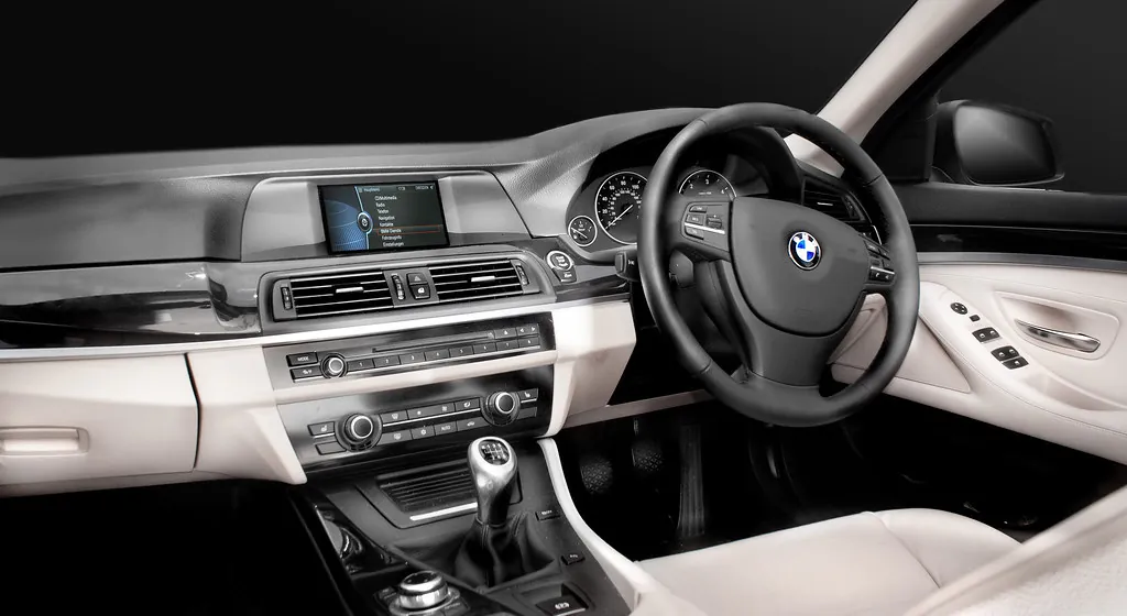 Clean car interior with light cream leather seats and door panels and a dark dashboard